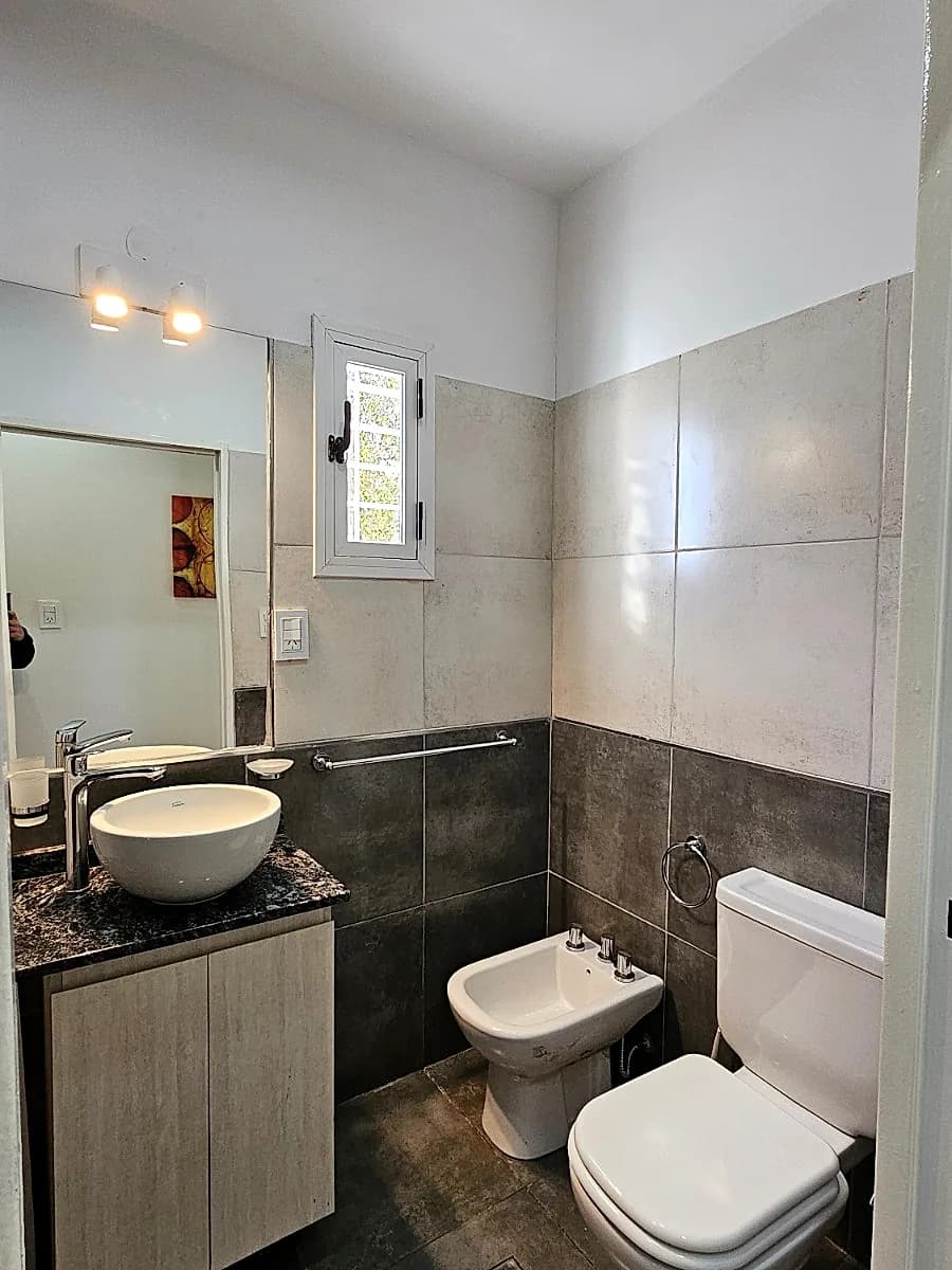 Baño completo con inodoro, bidet, bacha de apoyo, espejo y ventana