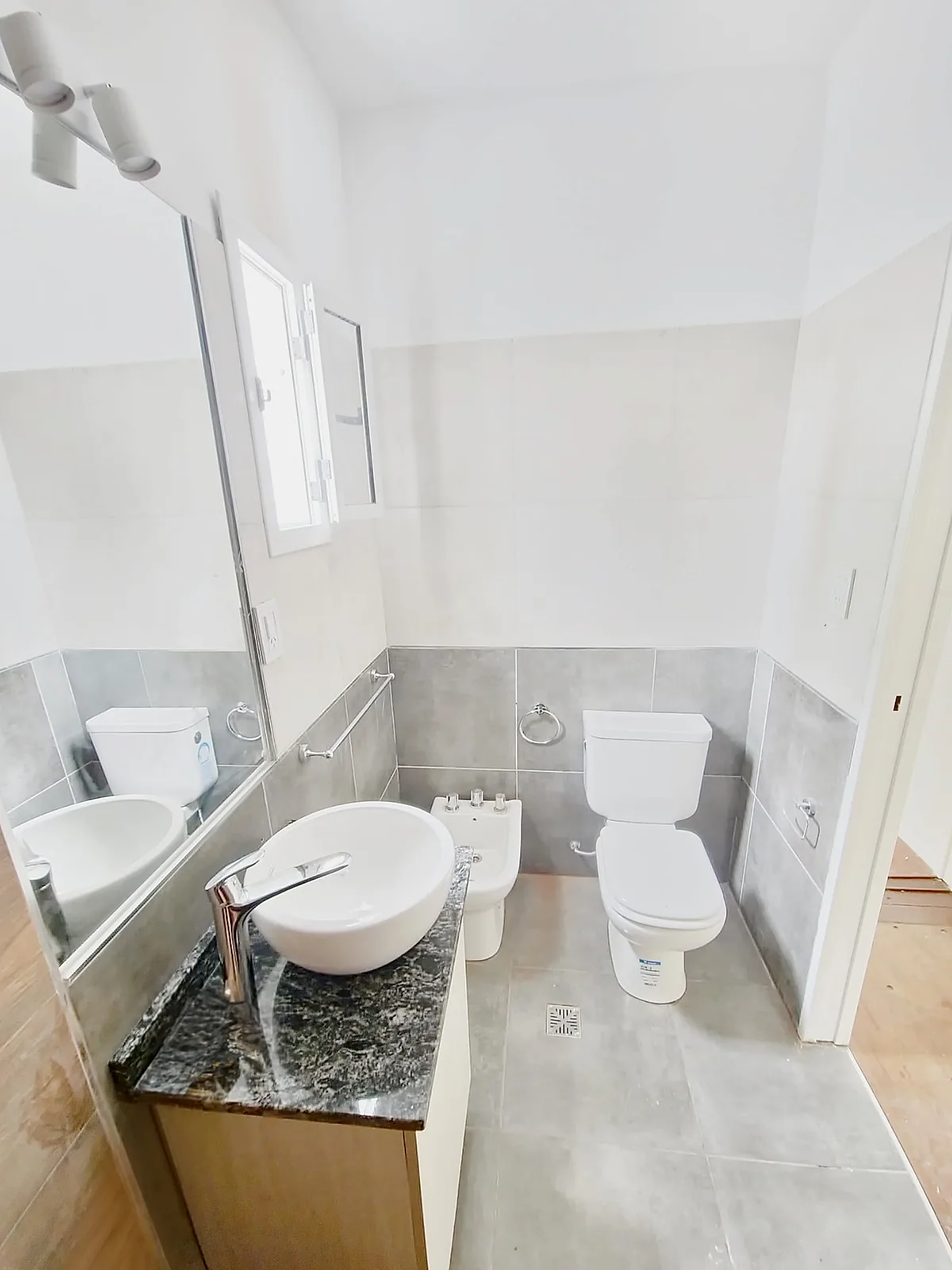 Baño luminoso con mesada de granito, bacha de apoyo, inodoro y bidet