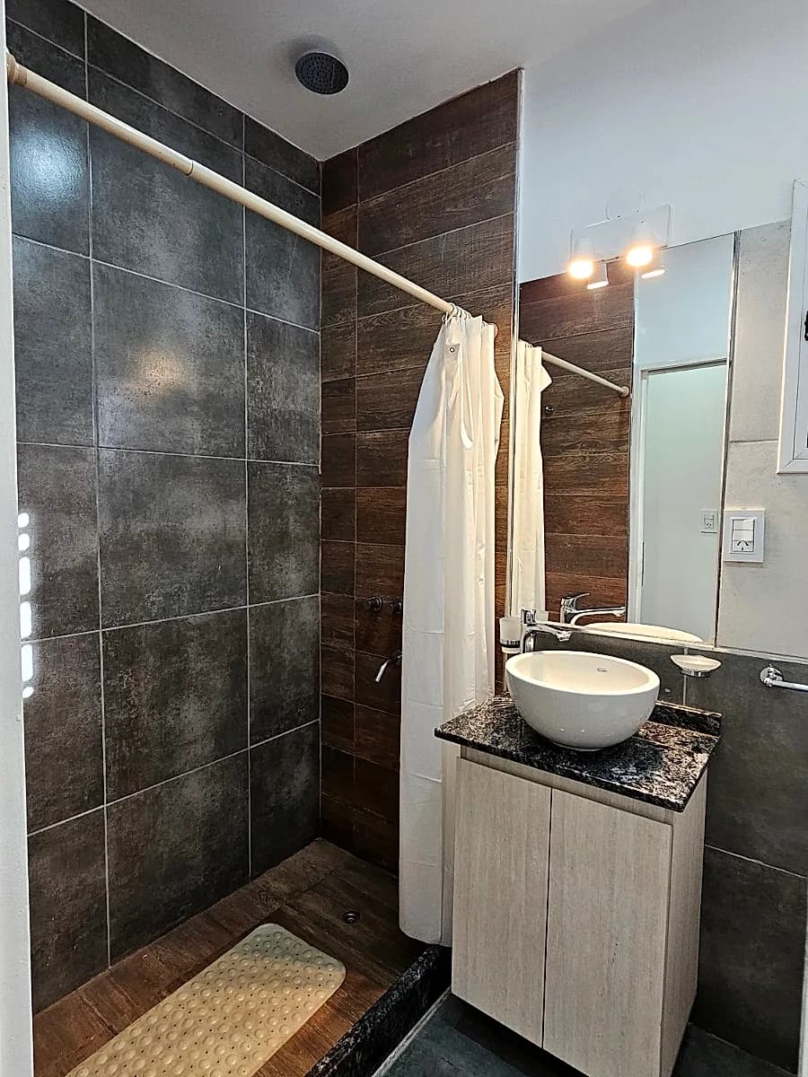 Baño completo con ducha revestida, bacha de apoyo y mesada de granito