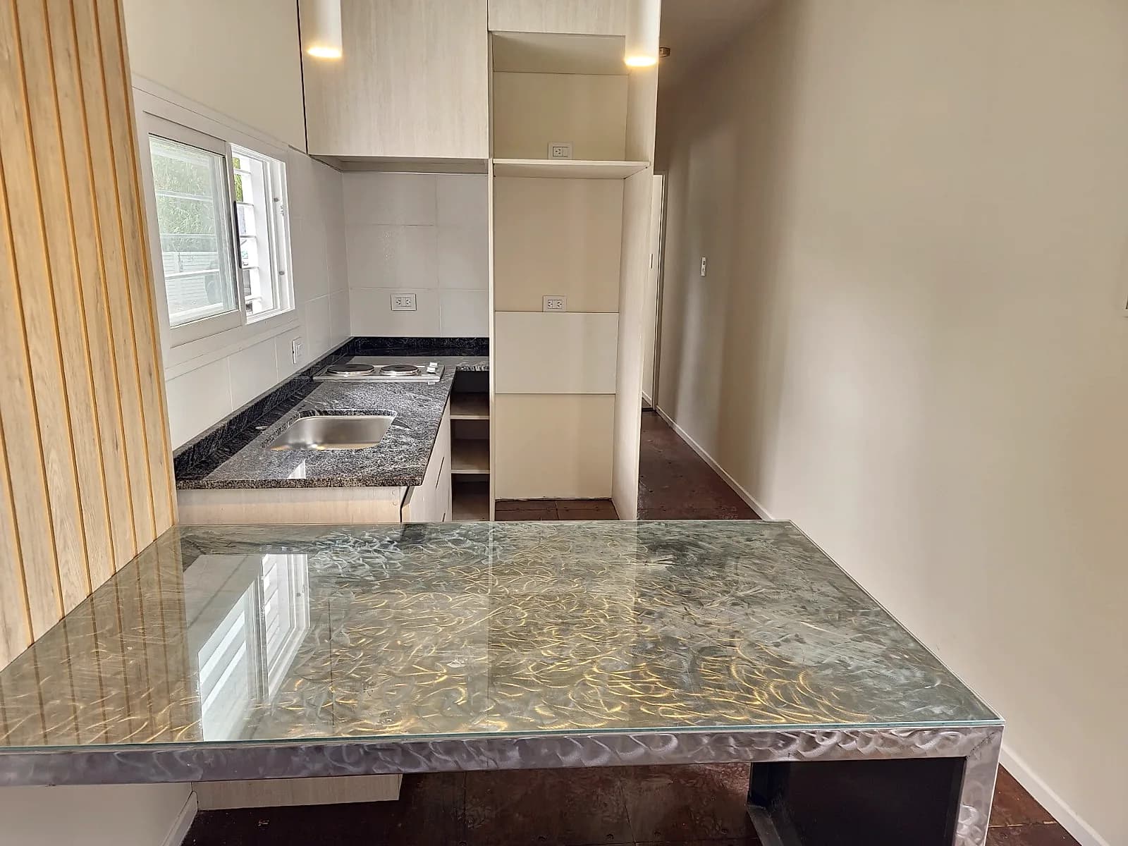 Cocina integrada con mesada de granito, barra vidriada y muebles a medida