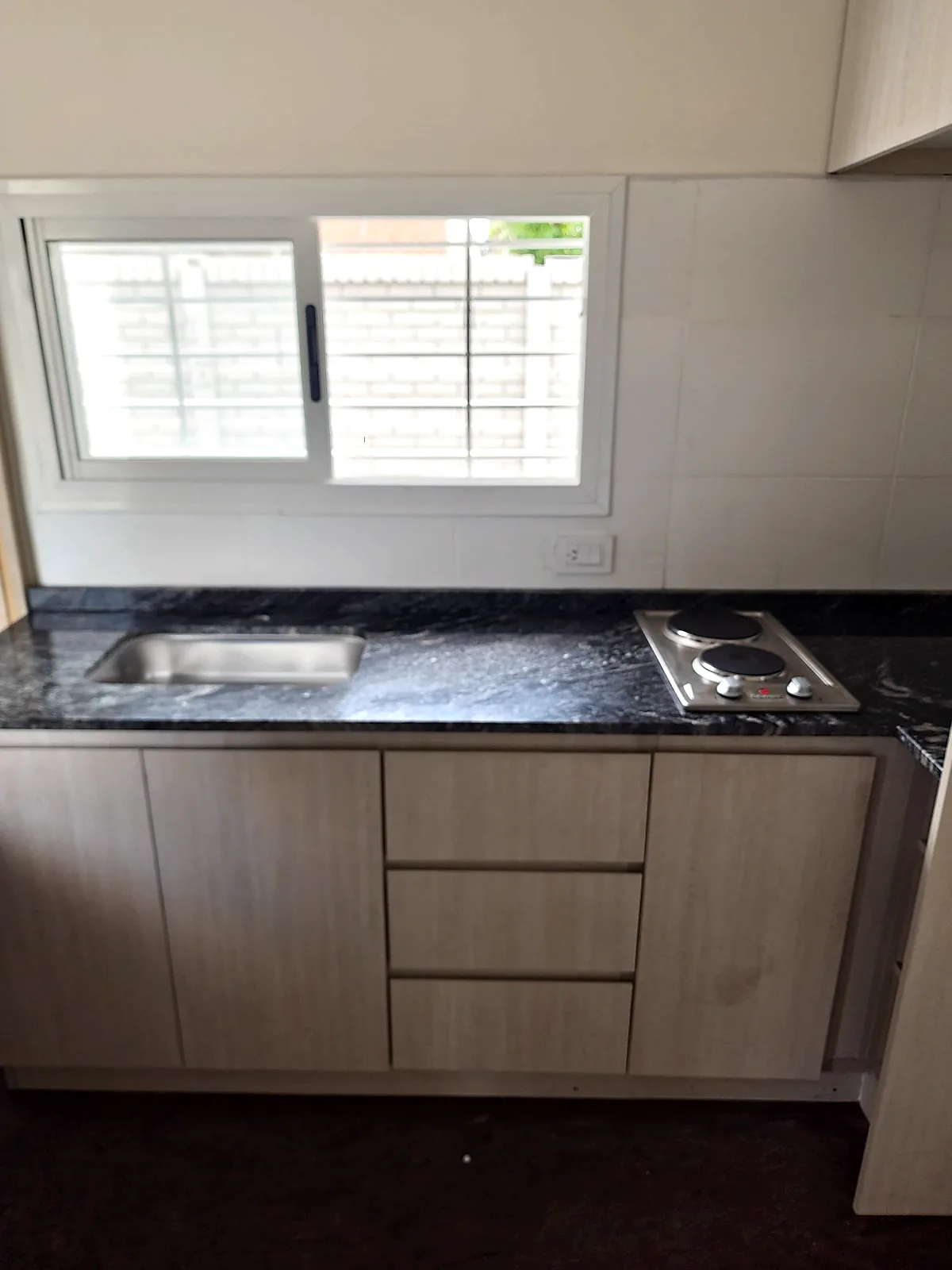 Mesada de granito con bacha, anafe eléctrico y muebles de guardado