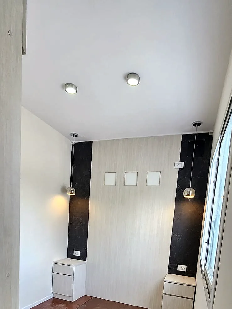 Dormitorio del Eco Home con mesas de luz y luminarias colgantes