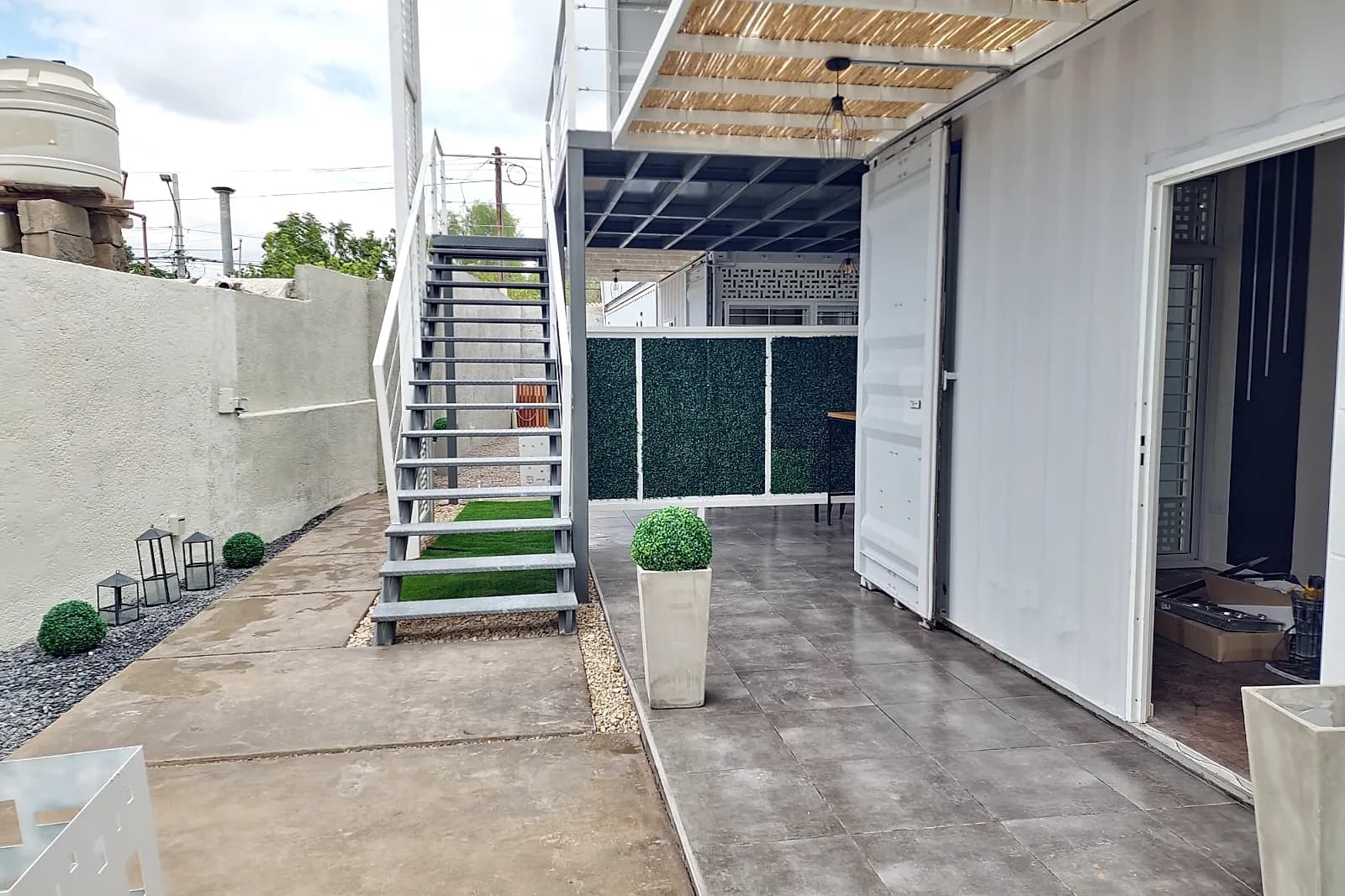 Galería exterior con escalera metálica hacia el segundo nivel del Eco Home