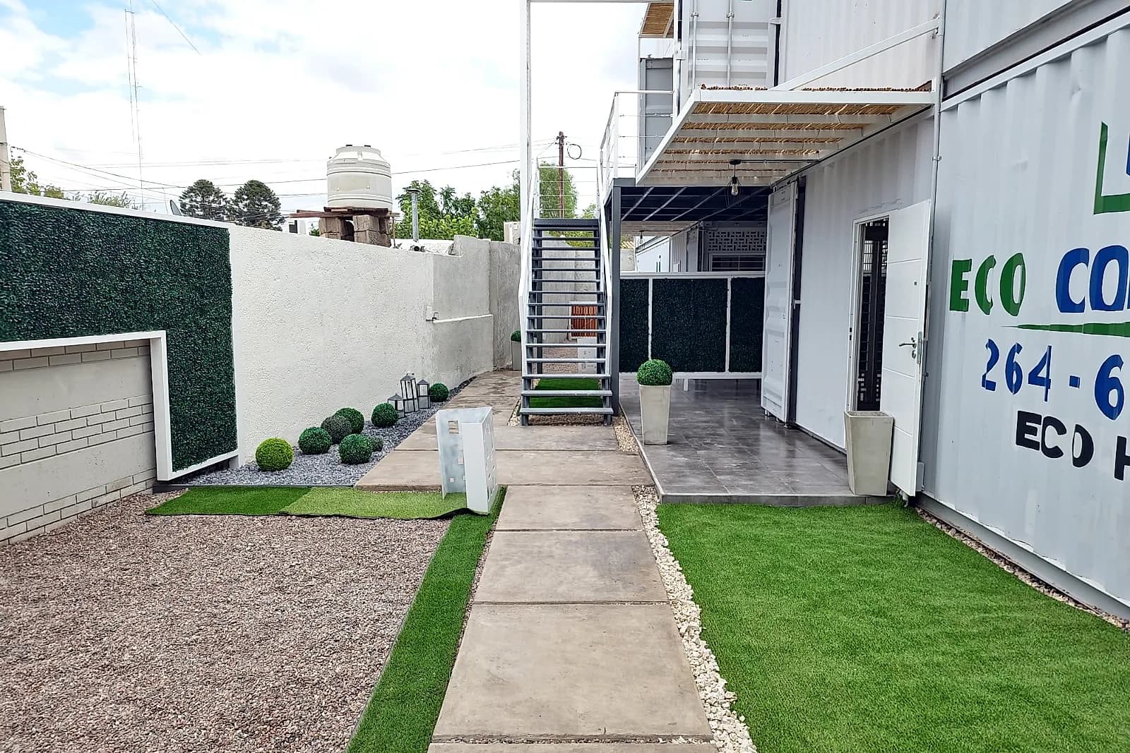 Vista lateral del conjunto Eco Home de dos niveles con patio, escalera y áreas verdes