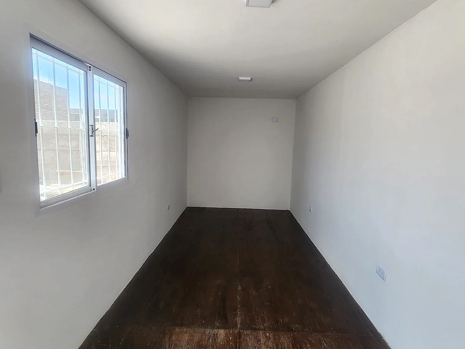 Interior terminado de un Eco Office con iluminación, tomas eléctricas y ventana con rejas
